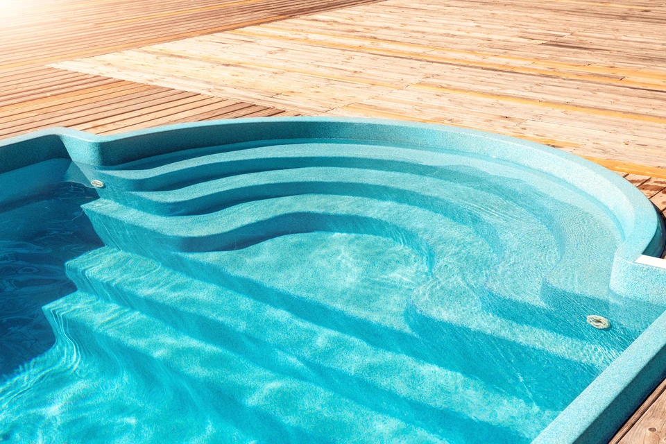 Piscine extérieure avec jets d'hydromassage en fonctionnement, entourée d'un deck en bois naturel