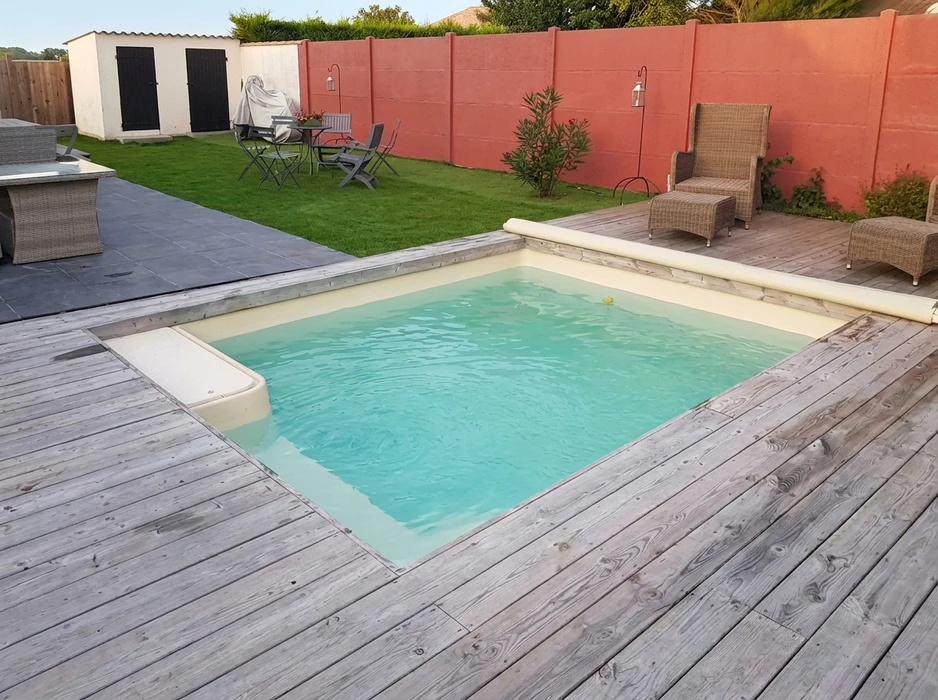 Piscine rectangulaire semi-enterrée à liner beige, intégrée dans une terrasse en bois composite grisé