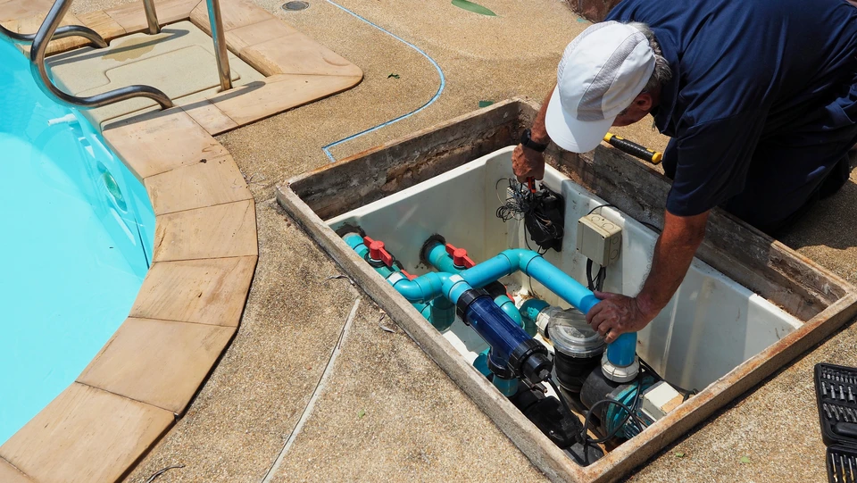 Photographie d'une équipe de professionnels (3-4 personnes) sur le chantier d'une piscine en construction, portant des tenues professionnelles et des équipements de sécurité appropriés (gilets haute visibilité si nécessaire). L'équipe doit apparaître engagée et professionnelle, discutant ou travaillant ensemble autour d'une piscine en cours de construction ou de terrassement. La scène doit refléter la collaboration, le professionnalisme et la passion pour le métier. L'arrière-plan doit montrer clairement un chantier de piscine avec travaux en cours. La photo doit être prise en lumière naturelle, en journée, avec une qualité nette et professionnelle.